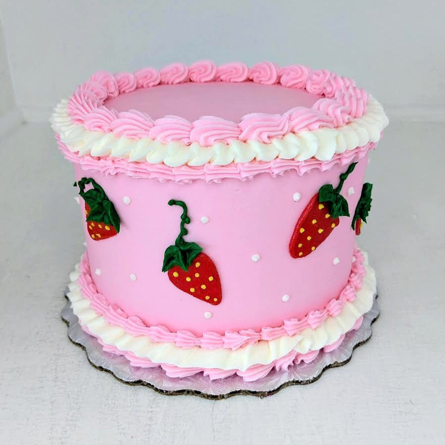 Pink cake with white frosting and strawberry decorations on a white background