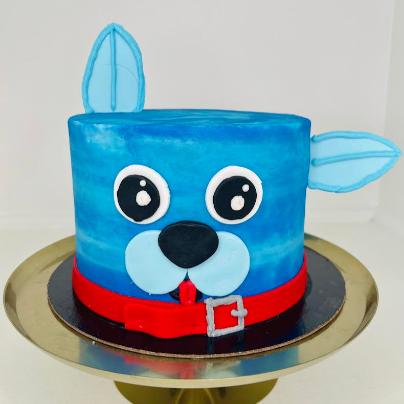 Blue dog-themed cake with a red collar on a white background