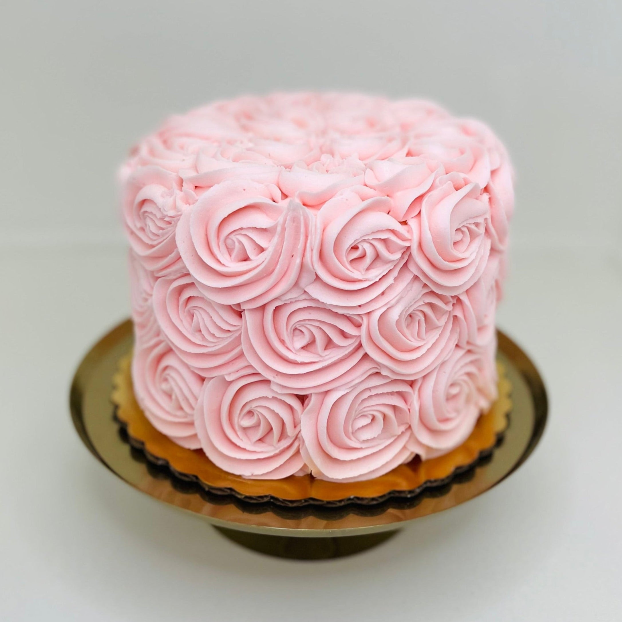 A 6-inch round vanilla cake with pink buttercream rosettes, designed for 12 servings.