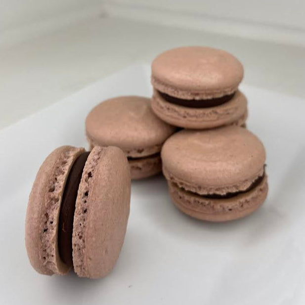 Stack of chocolate macarons on a white surface