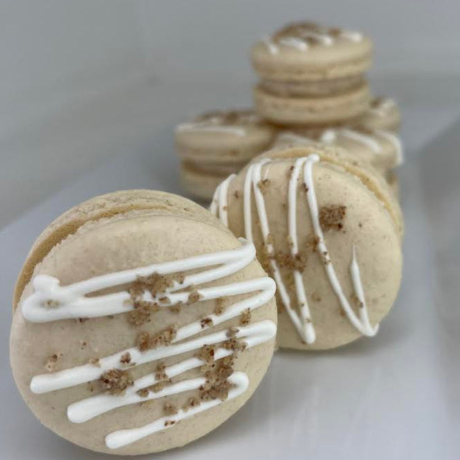 Macarons with white drizzle and brown specks on a light gray background