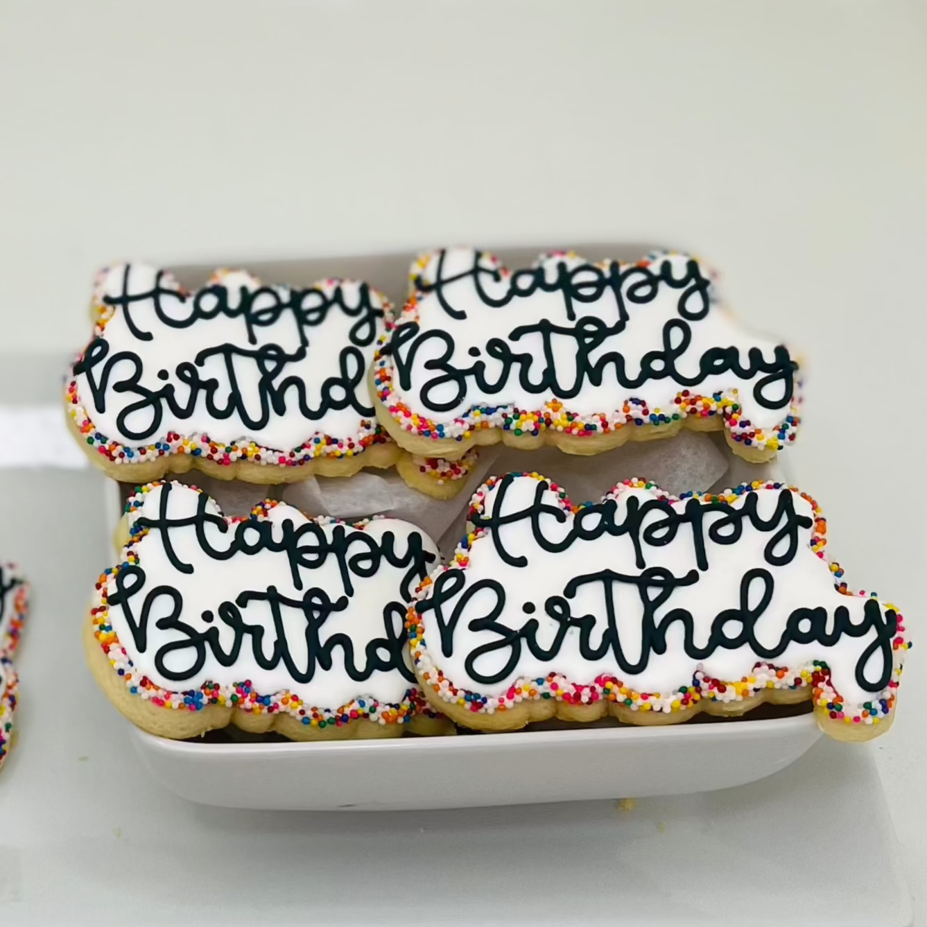 A plate of cookies decorated with 'Happy Birthday' messages and colorful sprinkles.