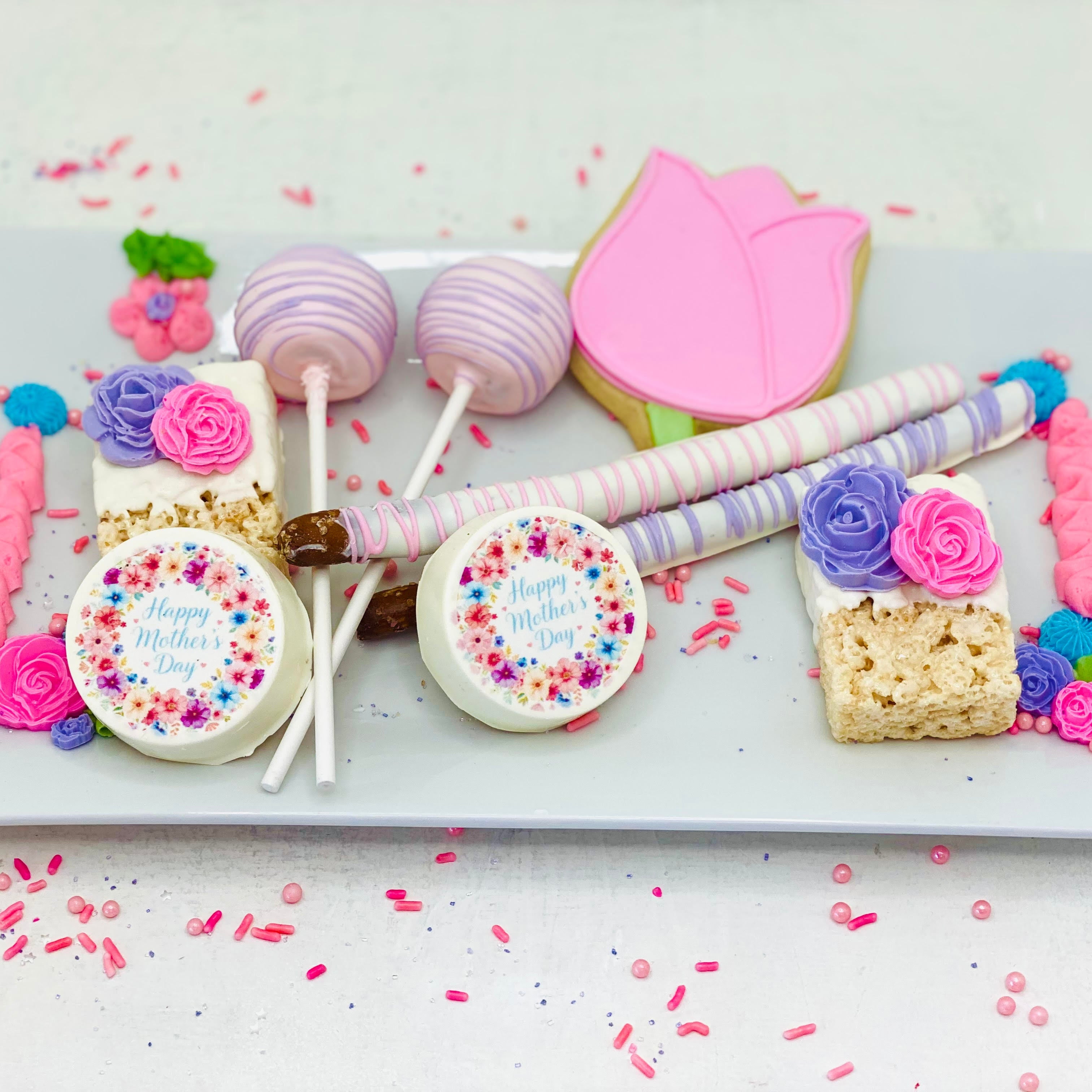 Mother’s Day Sweets Box – 8x8 Window Gift Box
(2) Cake Pops
(2) Chocolate Dipped Rice Krispy Treats
Flower-Shaped Royal Iced Sugar Cookie
(2) Chocolate Covered Oreos