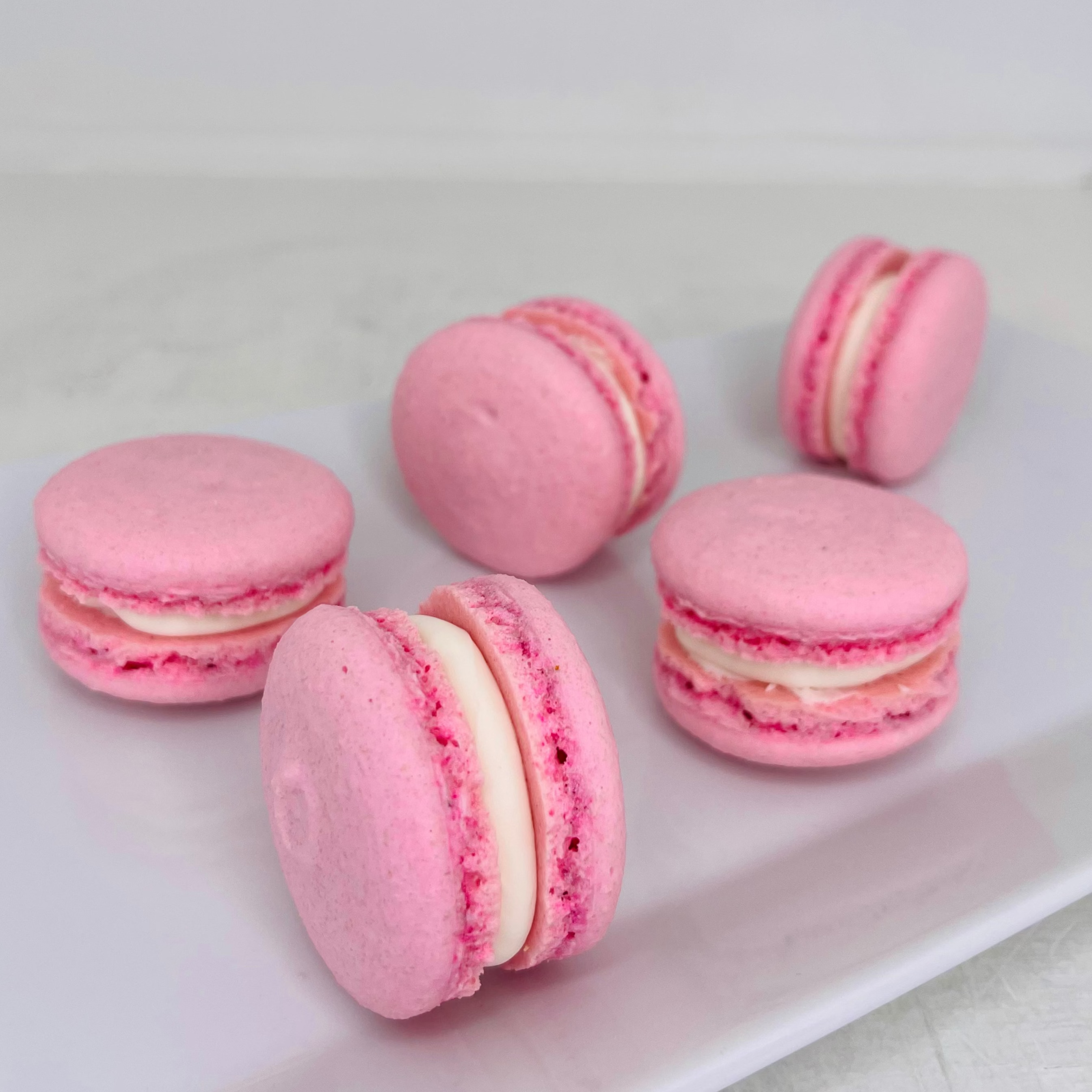Pink macarons with white filling on a white plate
