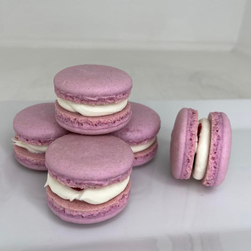 Stack of purple macarons with white filling on a white surface