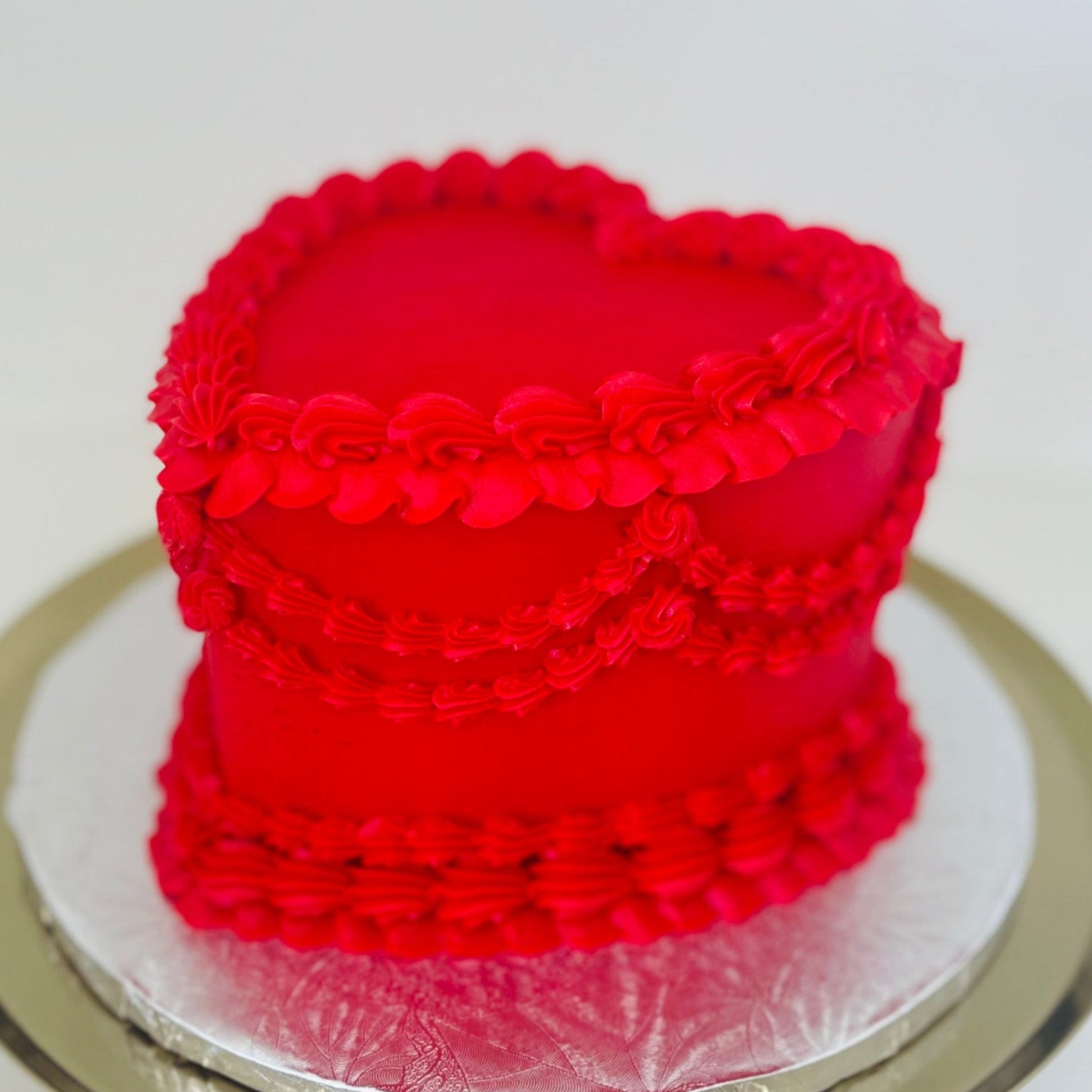A 6-inch heart-shaped red velvet cake with buttercream frosting, designed with vintage-style decorations on each layer.