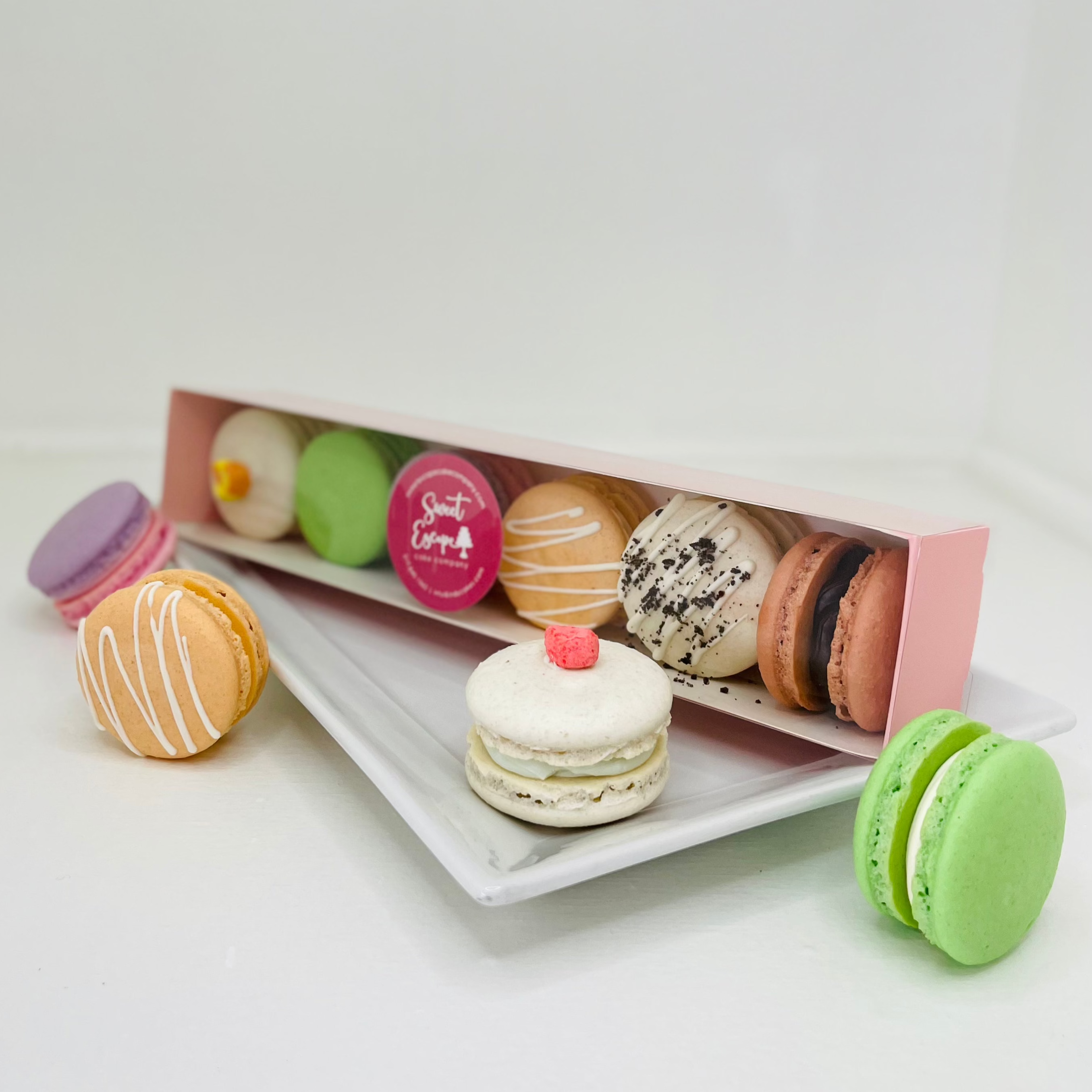 A box of six assorted macarons on a white plate, featuring a variety of colors and flavors.