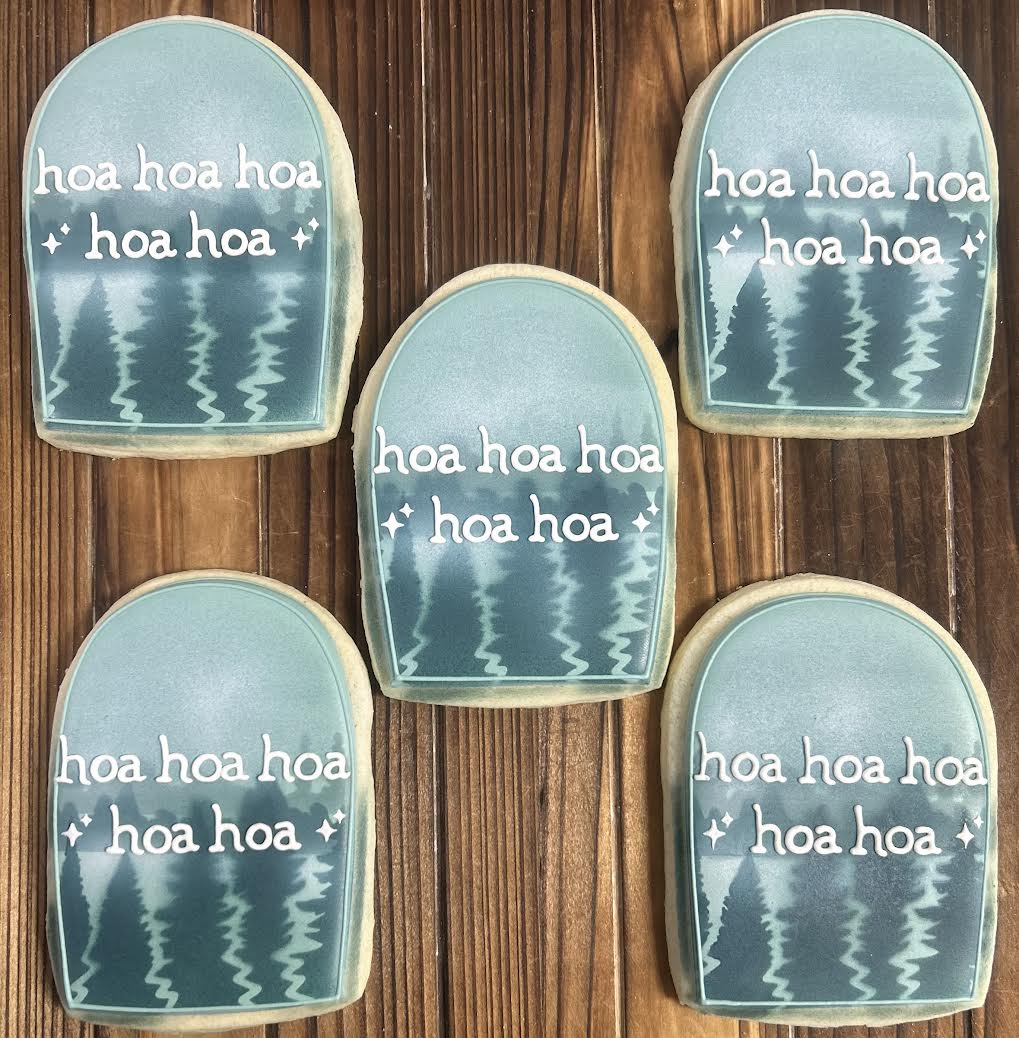 Five decorative cookies with 'hoa hoa' text on a wooden surface