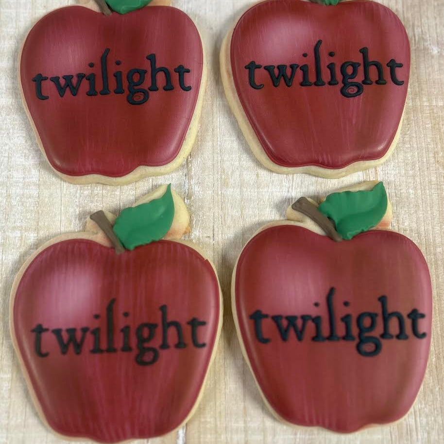 Four apple-shaped cookies with 'twilight' text on a textured surface